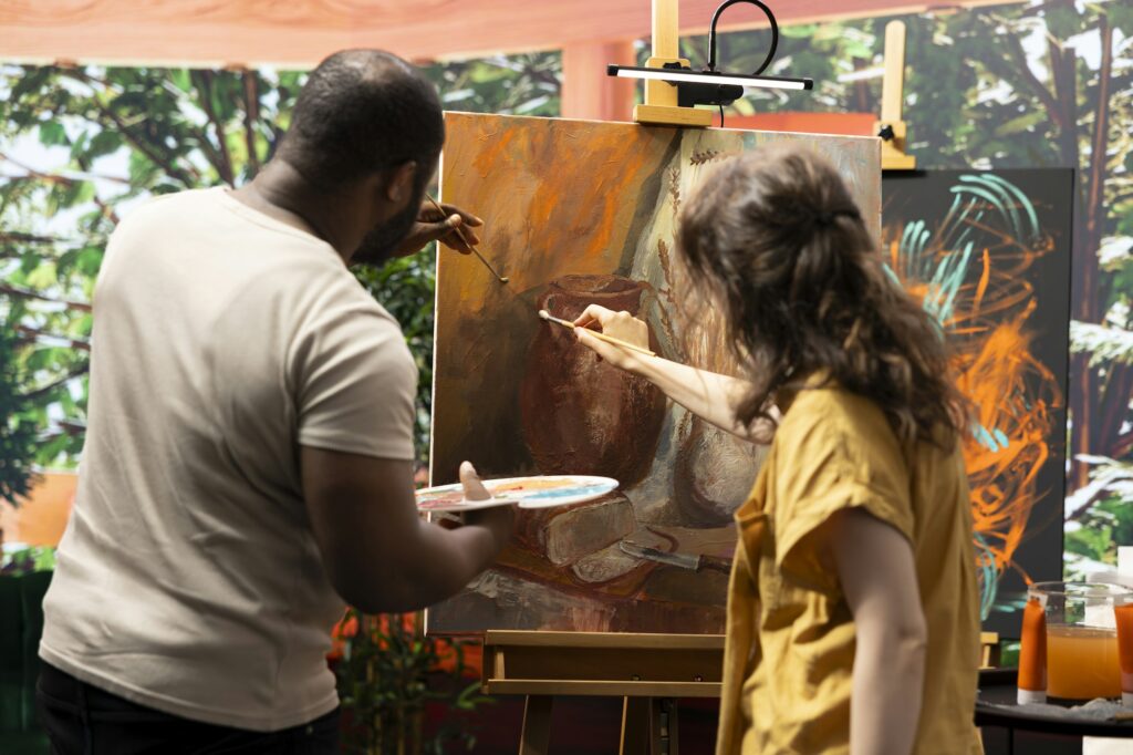 Diverse artists collaborating on colorful painting in art and craft workshop